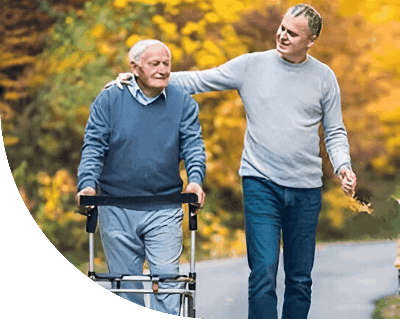 Young man walking with elderly man using a walker outdoors.