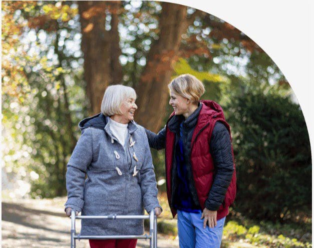Two women outdoors sharing a happy conversation in fall attire.