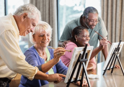 Seniors joyfully painting together on canvases indoors.