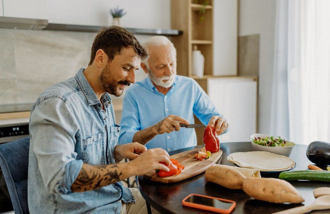 Two men cooking together in a kitchen, preparing bell peppers.