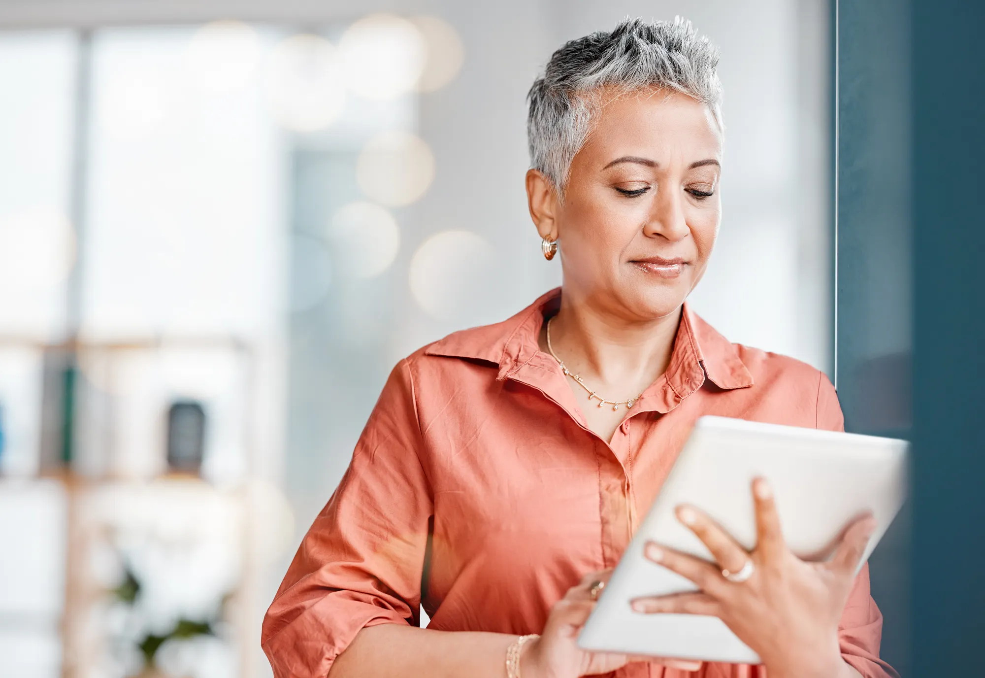 A mature woman using a tablet with a focused expression.